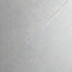 May include: A close-up of a light grey textured surface. The surface is smooth and has a subtle sheen.