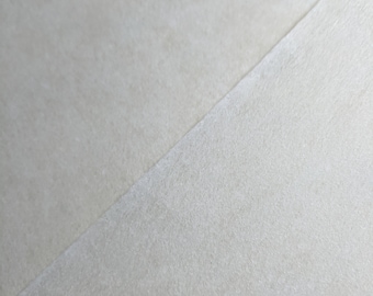 May include: A close-up of a light grey textured surface. The surface is smooth and has a subtle sheen.