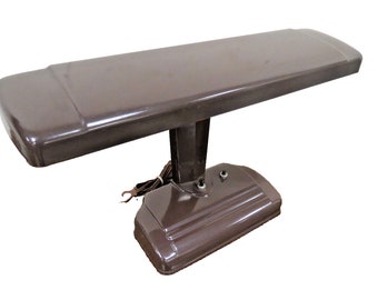 May include: A brown vintage desk lamp with a long rectangular shade and a round base. The lamp has a cord and plug.