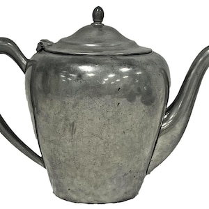 May include: A vintage silver teapot with a curved handle and a long spout. The teapot has a lid with a small knob on top. The metal has a slightly aged appearance, suggesting it is an antique or vintage item. The teapot is designed for brewing and serving tea.