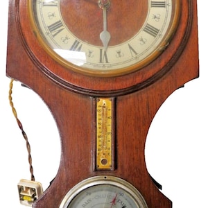 May include: Antique wooden wall clock with a round face featuring Roman numerals and ornate hands. Below the clock face is a thermometer and a barometer. The clock has a dark brown finish and a vintage aesthetic.