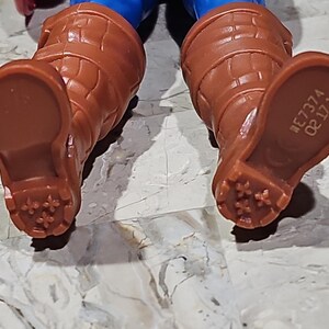 May include: Close-up of the bottom of a pair of brown boots with a textured sole. The boots have a number printed on the bottom: "#E7374 0811".
