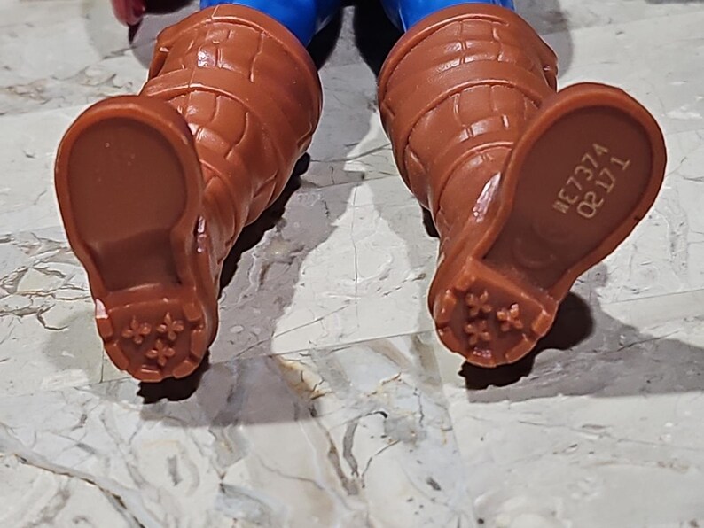 May include: Close-up of the bottom of a pair of brown boots with a textured sole. The boots have a number printed on the bottom: "#E7374 0811".