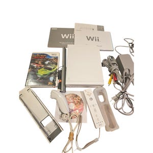 Peut inclure: Une console Nintendo Wii blanche avec des accessoires, dont une télécommande, une barre de capteurs, un adaptateur secteur et un disque de jeu. Sont également inclus des manuels d'instructions et un boîtier de jeu "Monster Trucks Mayhem".