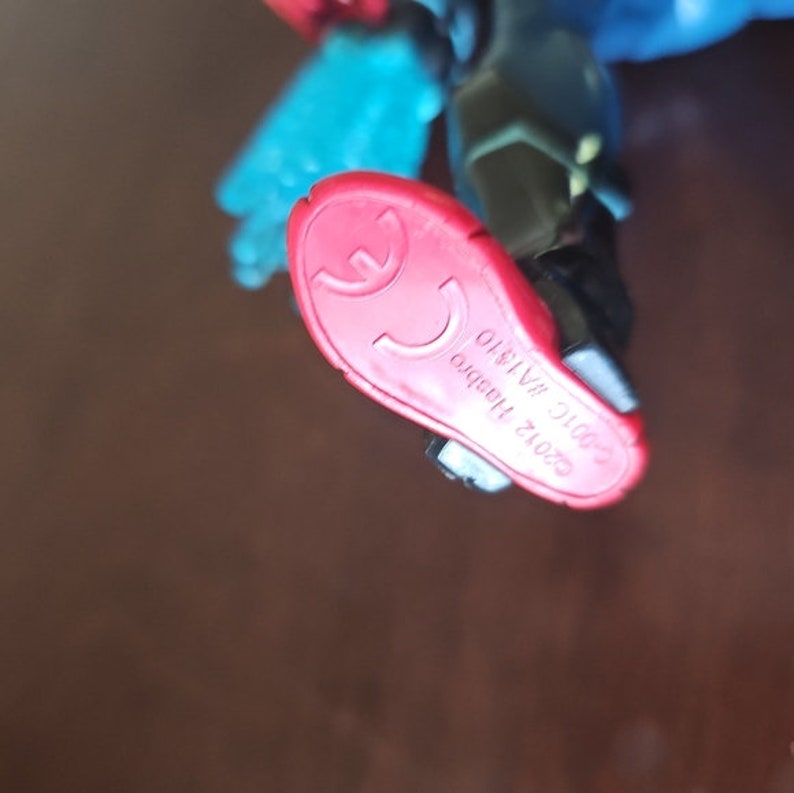 May include: Red and black action figure foot with the text "2012 Hasbro, Inc. Made in China 01819" printed on the bottom.