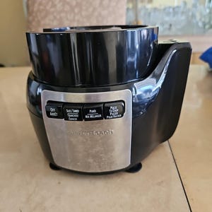 May include: Black and silver food processor with a variety of settings including off, slice/shred, puree, mix, and pulse to chop. The food processor is labelled "Cuisinart Beach".