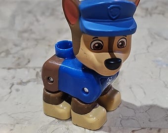 Puede incluir: Un perro de juguete de plástico azul y marrón con un sombrero azul. El perro tiene un cuerpo marrón, patas azules y un sombrero azul con una estrella blanca.
