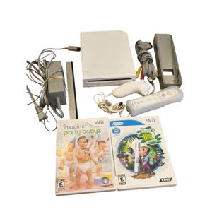 Peut inclure: Une console Nintendo Wii blanche avec une télécommande, un nunchuk et deux boîtiers de jeu. Les boîtiers de jeu sont pour "Imagine Party Babyz" et "Dood's Big Adventure". La console a un cordon d'alimentation et une barre de capteur.