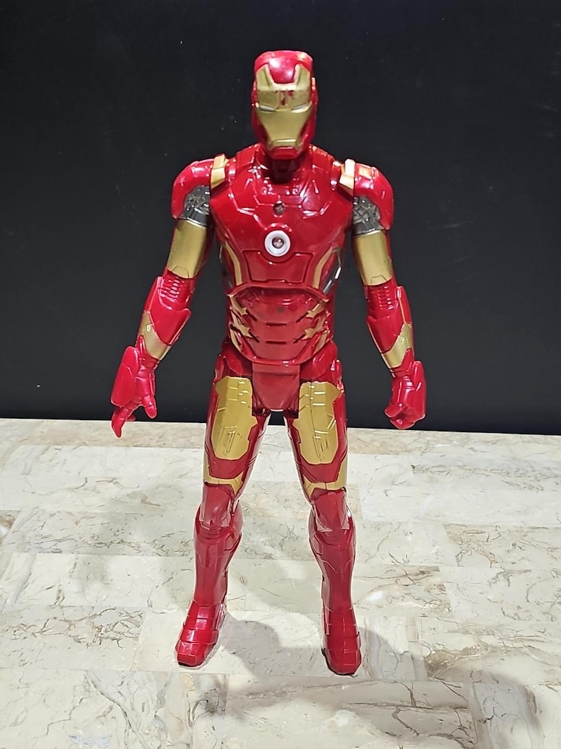 Pu&ograve; includere: Figurina di Iron Man rossa e dorata con un petto che si illumina. La figura &egrave; in piedi su una superficie bianca.