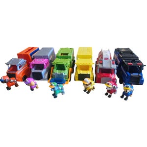 Puede incluir: Una colección de camiones de juguete y figuras de personajes coloridos. Los camiones son de varios colores, incluyendo naranja, rosa, verde, amarillo, rojo y azul. Cada camión tiene un diseño único. Las figuras son de personajes de dibujos animados.