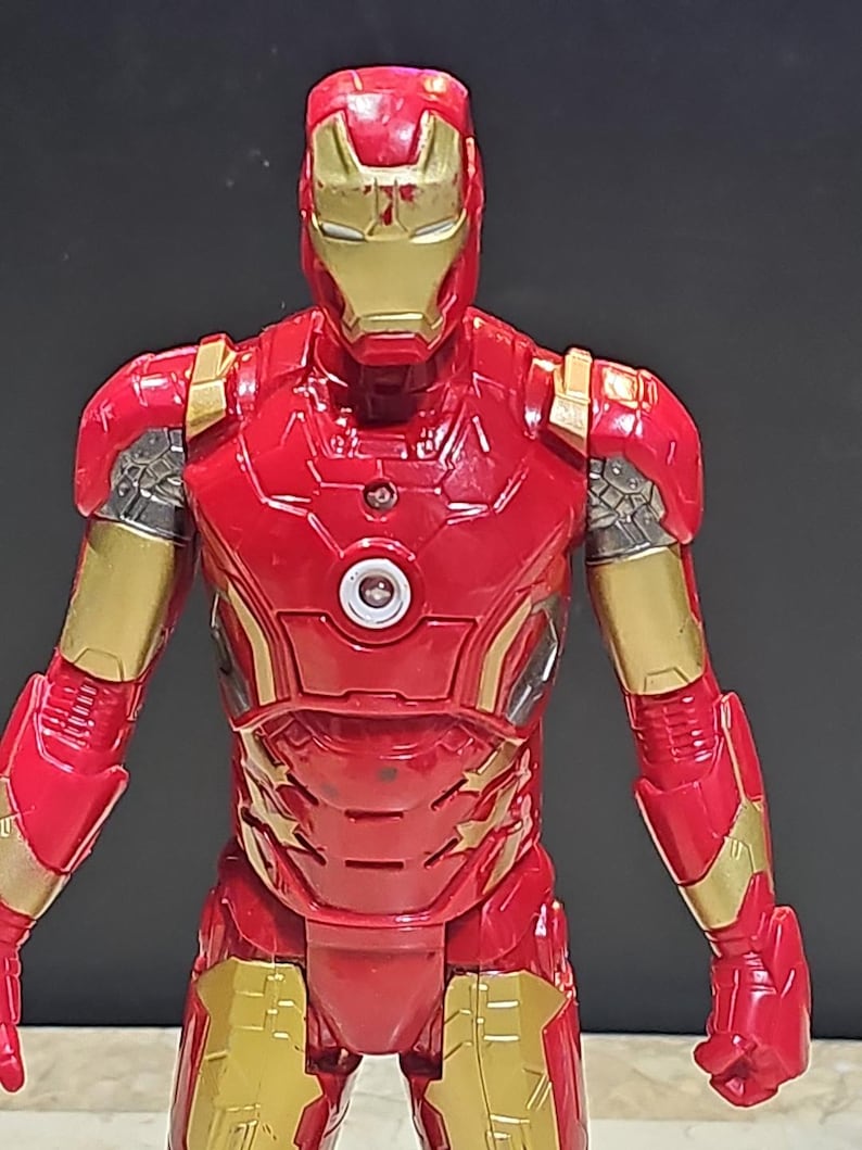 Pu&ograve; includere: Figurina di Iron Man rossa e dorata con un petto che si illumina. La figura &egrave; dettagliata ed &egrave; in posa con le braccia distese.