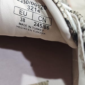 May include: Close-up of the inside of a sneaker. The label shows the size EU 38, CN 245/86, and the text "MADE IN TURKEY". The shoe has a snakeskin pattern.