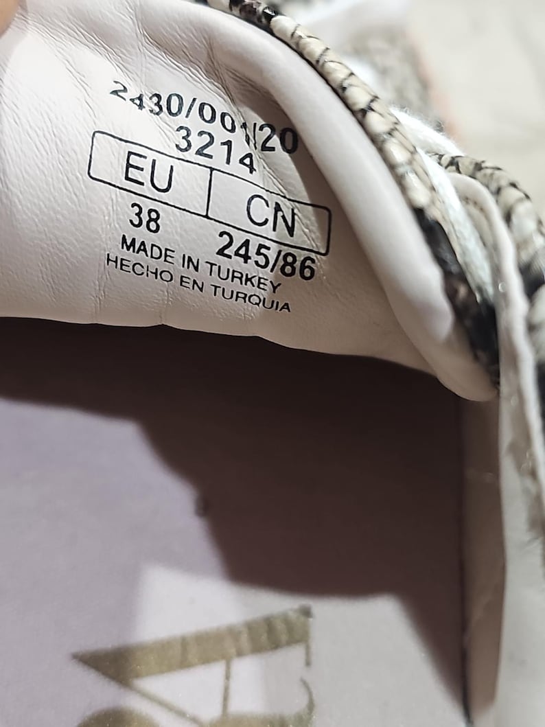 May include: Close-up of the inside of a sneaker. The label shows the size EU 38, CN 245/86, and the text "MADE IN TURKEY". The shoe has a snakeskin pattern.