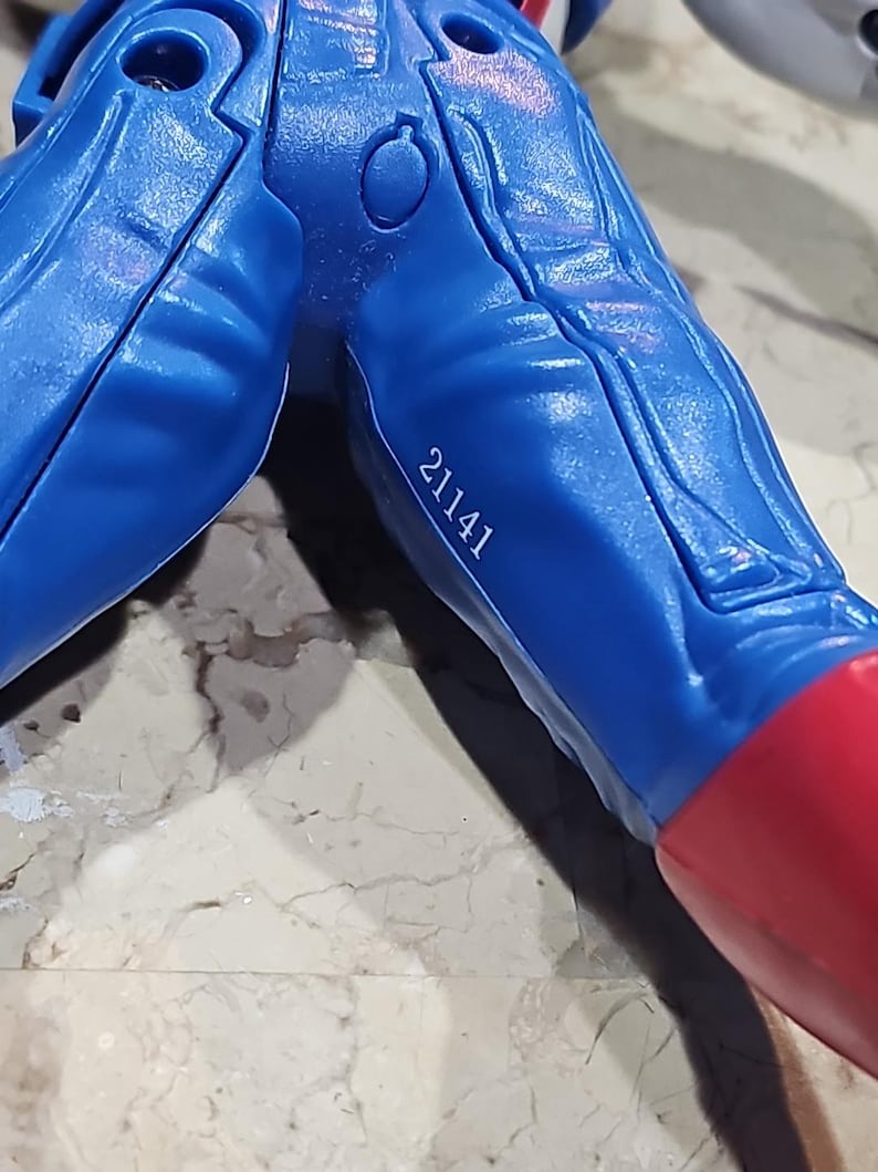 May include: Close-up of a blue plastic toy figure's lower body with a red boot and the number 21141 printed on the leg.