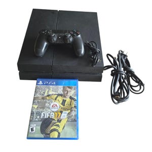 以下が含まれることがあります： 黒いPlayStation 4ゲーム機、同色の黒いワイヤレスコントローラー、2本の黒い電源・データケーブル、そして黄色と黒のユニフォームを着たサッカー選手が表紙に描かれた青いケース入りのFIFA 17ビデオゲーム。