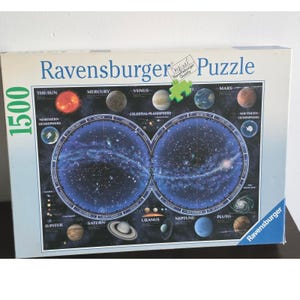 May include: A Ravensburger 1500-piece jigsaw puzzle box featuring a celestial planisphere. The box displays a dark blue space background with illustrations of the Sun, planets, and two circular star maps labeled by month.