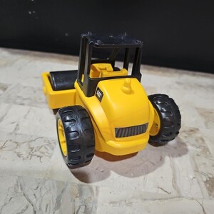 Puede incluir: Un veh&iacute;culo de construcci&oacute;n de juguete amarillo con ruedas negras y una cabina negra. El veh&iacute;culo tiene la palabra "CAT" impresa en el lateral.