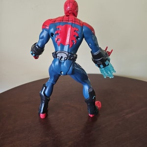 May include: A red and blue action figure of Spider-Man with web-shooters. The figure has a black belt and a red spider symbol on its back.