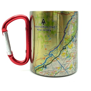 May include: A stainless steel travel mug with a red carabiner handle. The mug features a map of the Appalachian Trail in New Jersey with the text "Appalachian Trail New Jersey" and a symbol of a white triangle with a white A inside.