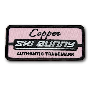 May include: A pink and black embroidered patch with the text "Copper Ski Bunny Authentic Trademark".