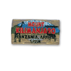 May include: A brown and tan embroidered patch with a mountain scene. The text reads "Mount Kilimanjaro, Tanzania, Africa 5,895m".