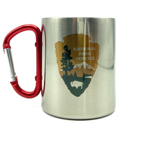 May include: A stainless steel travel mug with a red carabiner handle. The mug has a National Park Service logo with a mountain, tree, and buffalo.