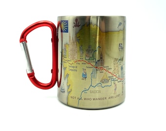 May include: A stainless steel travel mug with a red carabiner handle. The mug features a map of the Camino de Santiago pilgrimage route in Spain, with the text "NOT ALL WHO WANDER ARE LOST" printed on the bottom.