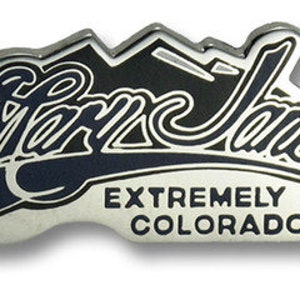 Peut inclure: Une épingle en métal argenté avec les mots "Mary Jane" dans une écriture stylisée, au-dessus des mots "EXTREMELY COLORADO". L'épingle présente un graphique de chaîne de montagnes et un fusil bleu foncé.