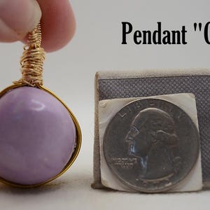 May include: A lavender-colored pendant with a gold wire wrap, held by a hand. The pendant is next to a quarter and a small gray box. The text "Pendant "C"" is above the pendant.
