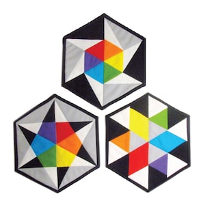 Könnte beinhalten: Drei sechseckige Stoffuntersetzer mit einem geometrischen Sternmuster in der Mitte. Die Untersetzer sind aus schwarzem, weißem, grauem, rotem, orangefarbenem, gelbem, grünem, blauem und violettem Stoff.