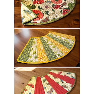 Pode incluir: Um conjunto de três saias para árvore acolchoadas em forma semicircular. A superior apresenta uma estampa floral e de borboletas com borda verde. A central tem painéis listrados em amarelo, verde e branco com borda amarela. A inferior tem painéis vermelhos.
