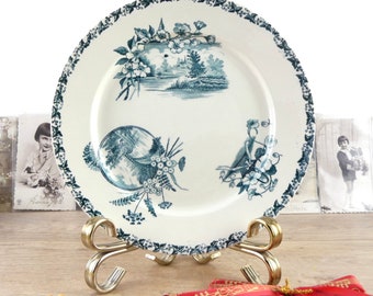 May include: A vintage blue and white porcelain plate with a floral design and a landscape scene. The plate is on a decorative stand.