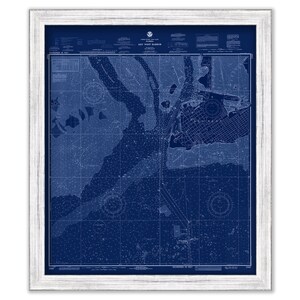 May include: A vintage nautical chart of Key West Harbor, Florida, printed in blue ink on a white background. The chart shows the coastline, waterways, and landmarks of the area. The chart is framed in a white frame.