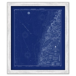 May include: A vintage nautical chart of Chesapeake Bay, printed in white on a dark blue background. The chart includes detailed markings and lines indicating depths, shoals, and other navigational features. The chart is framed in a white wood frame.