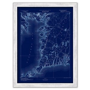 May include: A vintage map of the Massachusetts coastline, printed in blue ink on a dark blue background. The map shows the towns and cities along the coast, as well as the surrounding waterways. The map is framed in a white frame.
