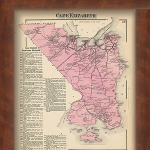May include: An antique map of Cape Elizabeth, Maine, printed in black and white with pink highlights. The map shows the town's streets, roads, and landmarks, including the coastline and surrounding islands. The map is framed in a brown wooden frame.