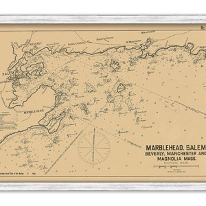 May include: A framed nautical chart of Marblehead, Salem, Beverly, Manchester, and Magnolia, Massachusetts. The map is in sepia tones with black text and lines, and includes a compass rose and measurements in nautical miles. The frame is white.