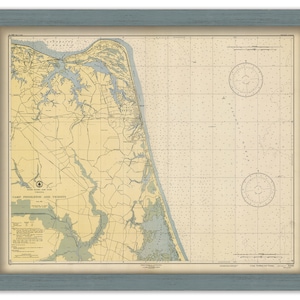 May include: Framed vintage map of Camp Pendleton and vicinity, Virginia, in a blue wooden frame. The map features detailed coastlines, waterways, and grid lines, with compass roses. The map is printed on aged paper.