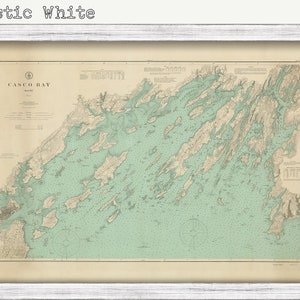 May include: A vintage map of Casco Bay, Maine, printed on aged paper with a rustic white frame. The map shows the coastline and islands of the bay in detail, with a light green color for the water and brown lines for the land.