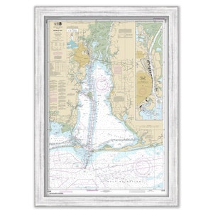May include: A nautical chart of Mobile Bay, Alabama, framed in white. The chart shows the coastline, waterways, and navigational aids. The chart is titled "Mobile Bay" and includes a legend and scale.