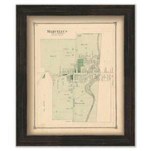 May include: An antique map of Marcellus, New York, printed in black and white with green accents. The map shows the layout of the town with streets, blocks, and buildings. The map is framed in a dark wood frame.