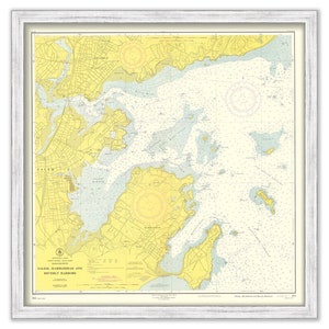 May include: A vintage nautical chart of Salem, Marblehead, and Beverly Harbors in Massachusetts. The chart is printed on yellow paper with blue lines and text. The chart shows the coastline, islands, and waterways of the area. The chart is framed in a white frame.