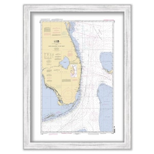 May include: A nautical chart of the coast of Florida from Cape Canaveral to Key West. The chart is printed on paper and framed in a white frame. The chart shows the coastline, islands, and waterways of the area. It also includes navigational information such as depths, buoys, and lighthouses.