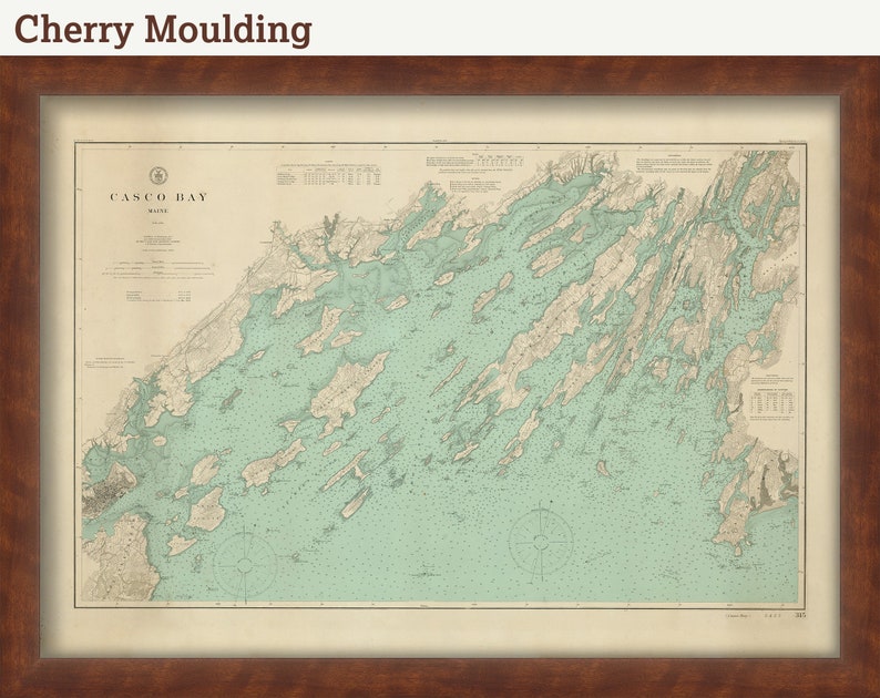 May include: A vintage map of Casco Bay, Maine, framed in a cherry wood frame. The map is printed on cream paper with blue and green accents. The title "Casco Bay, Maine" is printed in the top left corner.