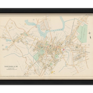 May include: An antique map of Dedham, Massachusetts, printed in black and white with yellow and green accents. The map shows streets, buildings, and bodies of water. The title "Dedham" is printed in the lower left corner. The map is framed in a black frame.