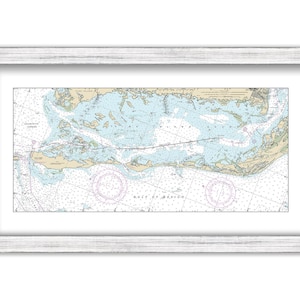 May include: A nautical chart of the waters around the Florida Keys, showing the islands, inlets, and channels. The chart is printed in blue, green, and brown, with white lines for the depths. The chart is framed in a white frame.