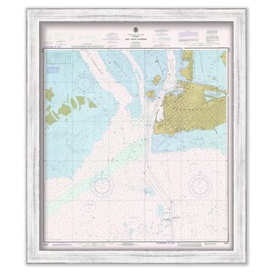 May include: A nautical chart of Key West Harbor, Florida, with detailed markings for navigation. The chart is framed in a white wood frame.