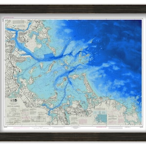 May include: A nautical chart of Boston Harbor, showing the depth of the water in blue, with the surrounding land in white and gray. The chart is framed in a dark wood frame.