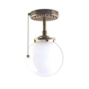 May include: A brass ceiling light fixture with a white globe shade and a pull chain. The fixture has a decorative, ornate brass base.