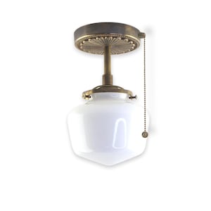 May include: A brass ceiling light fixture with a white glass shade and a pull chain. The fixture has a decorative brass plate with a floral design.